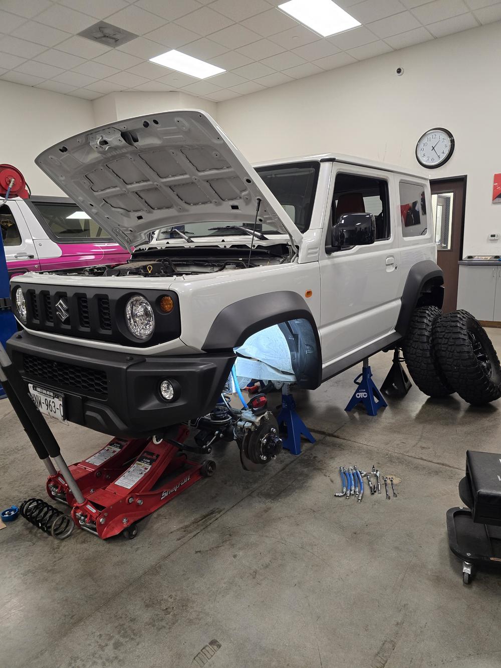 Students working on a vehicle's suspension during the King Shocks shop tour